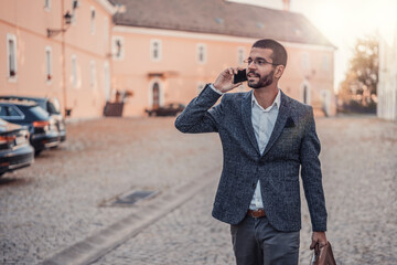 Young handsome businessman talking on mobile phone outdoors in city