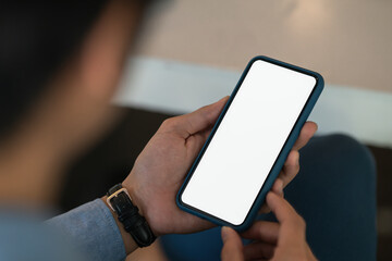 Businessman holding blank screen smartphone in the office room.