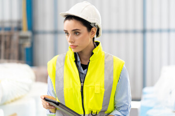 Female Inventory Manager working on digital tablet and checking quality of product at mask factory. Warehouse factory worker working at storage building.