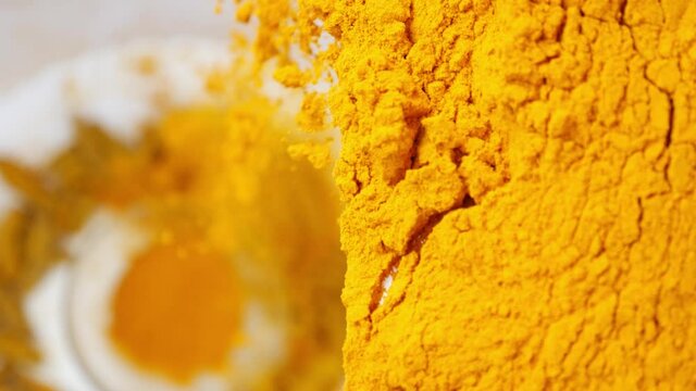 Close view of turmeric powder being dropped, View of turmeric powder