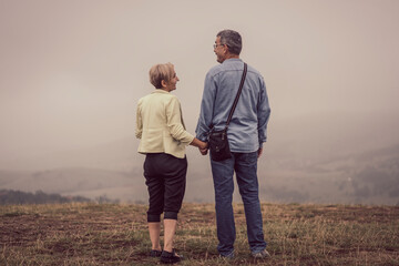 Beautiful older couple on mountain top surrounded with fog