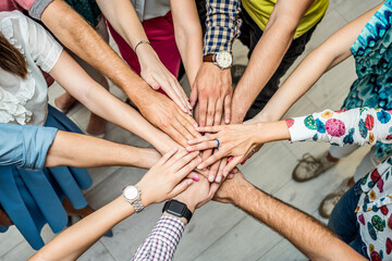 Large group of people standing in circle and stacking hands. Together making a successful team