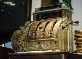 Vintage gold cash register in  shop window. Antiques. Commercial equipment of  past centuries.