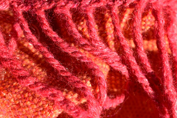 Fransen eines Tuches aus Wolle und Seite in Rosa und Orange als Hintergrund