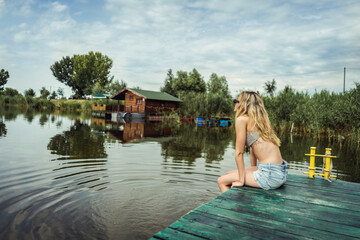 Beautiful young female enjoying summertime next to lake. River water at summer
