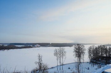 View of frozen Vyatka river at sunny winter day. Scenic russian landscape. Naked trees. A lot of snow.