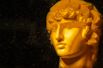 A statue. Plaster decorative golden statue of the head of Apollo.