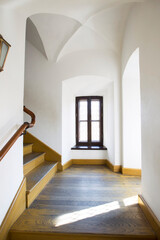 An empty hallway with a vaulted ceiling and a wooden staircase ..
