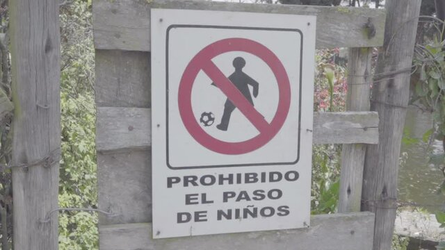 A forbidden sign symbol with a red circle and line over a kid playing soccer is on a door. The sign is in Spanish and translates to "Children pass forbidden".