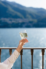 person watching a lake with glass of wine 