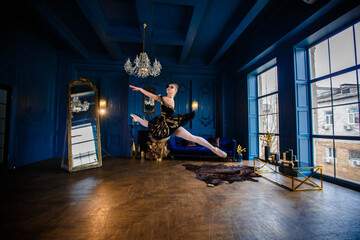 Fototapeta na wymiar Ballerina in a ballet tutu makes a jump in a blue interior