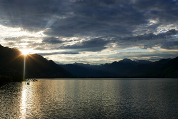 Morning sun rising behind the mountains at Lake Maggiore. Shot from Locarno, Switzerland.