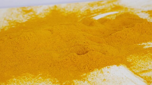 Close view of throwing turmeric powder over white background