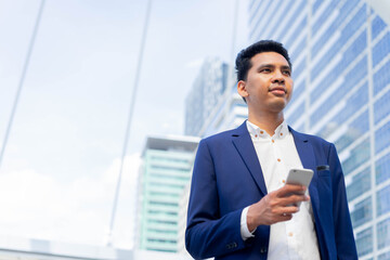 close up adult mixed race of middles eastern businessman holding smartphone and standing outside company over city building background for future vision concept