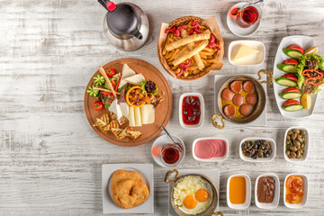 Traditional Turkish Breakfast served with traditional turkish tea on wooden table.