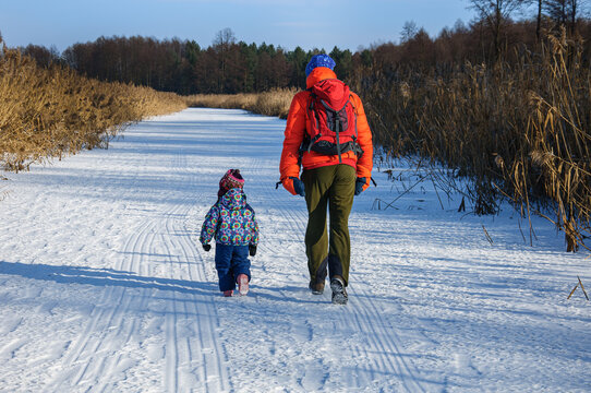 Dad and daughter are walking along the frozen river on a sunny day. Winter fun