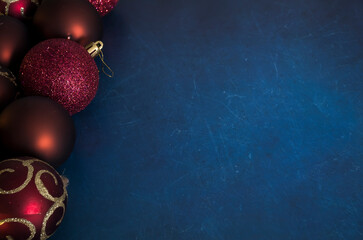 Dark festive holiday concept. Red Christmas baubles on dark blue scratched vintage background. Decorative design. Selective focus on sphere balls, blurred background.