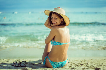 Beautiful young woman in bikini on vacation swimming in sea and enjoying in sand beach. Happy female enjoying summer time holiday on beach.