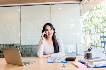 A business woman using a smartphone and smiling while working in the office
