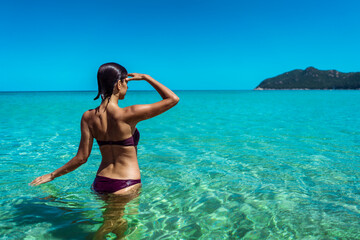 Beautiful young woman in bikini on vacation swimming in sea and enjoying in sand beach. Happy female enjoying summer time holiday on beach.
