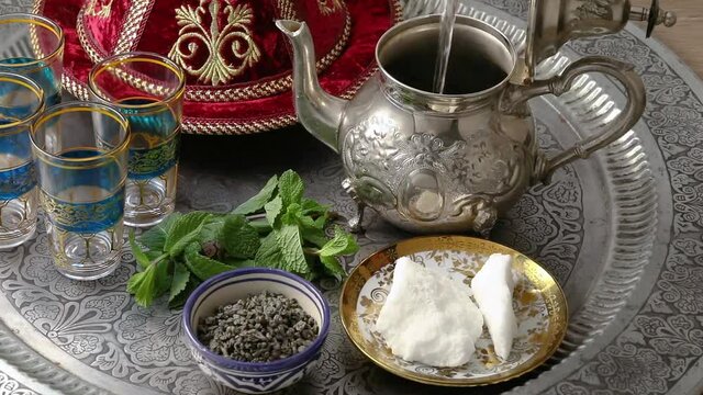 Making Moroccan mint tea with gunpowder tea leaves, sugar and hot water close up