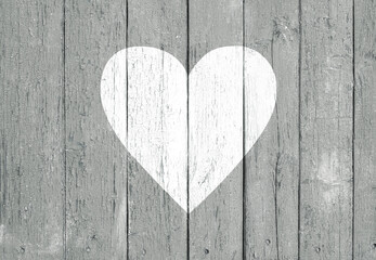 Old wooden board background with cracked gray paint and white heart shape