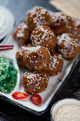 Closeup of fried pork meatballs served in teriyaki sauce and topped with sesame, selective focus