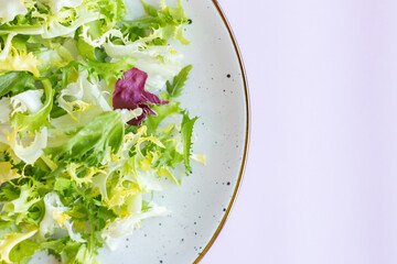 White ceramic plate with fresh salad on light pink background