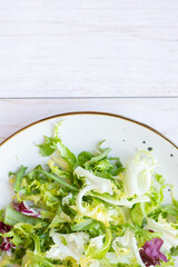 White ceramic plate with fresh salad on wooden background