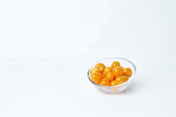 Glass container contains several cape gooseberries.  Exotic tropical fruits.