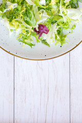 White ceramic plate with fresh salad on wooden background