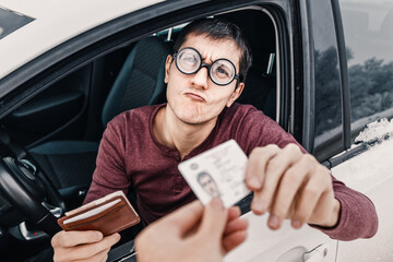 Funny nerd and geek in huge ridiculous glasses shows his drivers license. Concept of police checks...