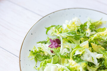 White ceramic plate with fresh salad on wooden background