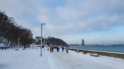 Winter walk. People walking on the Baltic sea boulevard in Gdynia, Poland. Gdynia is an important seaport of Baltic Sea in Poland.