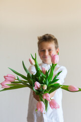 Young boy, kid child hands with pink tulips, flowers