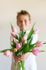 Young boy, kid child hands with pink tulips, flowers