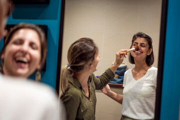 Beautiful young women getting ready for night out. Saturday night here we come. Girls putting on make up in bathroom