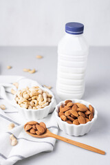 Cashews, almond nuts in white plates for making homemade milk. Alternative plant-based vegan drink, cooking. Replacement cow's milk. Source of protein, healthy fats. Diet food. Light white background