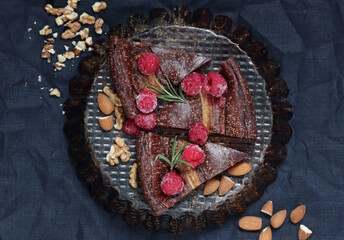 Chocolate vegan brownie cake with banana decorated with raspberry, walnut and rosemary, closeup, copy space, vegan eggfree desserts concept