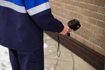 Close-up shot of man hand recording heat loss with infrared thermal camera outside home....
