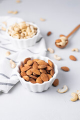 Natural organic roasted unpeeled almond, cashew nuts on a light background. The basis of norm fats and oils, the keto diet and a healthy snack. Nut oil is a source of vitamins.