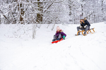 Children sliding down the snow path on sled
