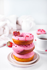 Cup of coffee and pink doughnuts on the white background. Valentine's Day concept.
