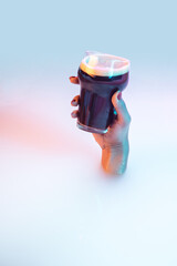 Touch. Close up female hand gesturing from the milk bath with soft white glowing in neon light. Copyspace for advertising. Modern neoned colors, foam. Holding stout dark beer glass. Drinks, alcohol.