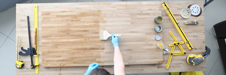 A joiner polishes a wooden surface. Carpenter tools lie on the table