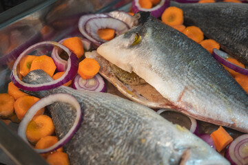 Gilthead bream (Sparus aurata) fish with carrots, lemon and onion prepared to be put in the oven