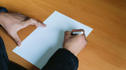 Mano escribiendo sobre un folio en blanco