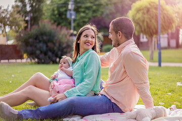 Beautiful young happy couple with baby in park outdoors. Love, parenthood, family, season and people concept - smiling couple. Parents  with their baby 