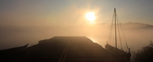 Viking ship at the jetty in fog at sunrise, banner