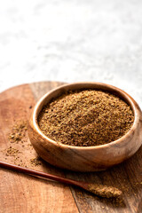 Ground flaxseeds in a wooden bowl on a gray background close-up. Copy space for text.